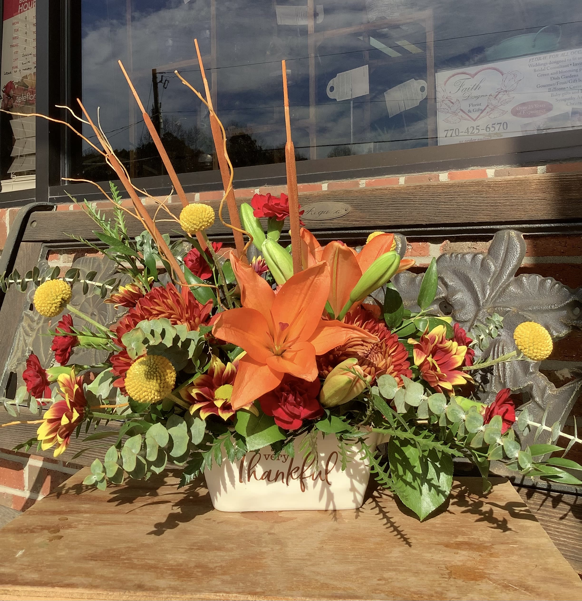 Orange lily and mixed flowers in a cream container