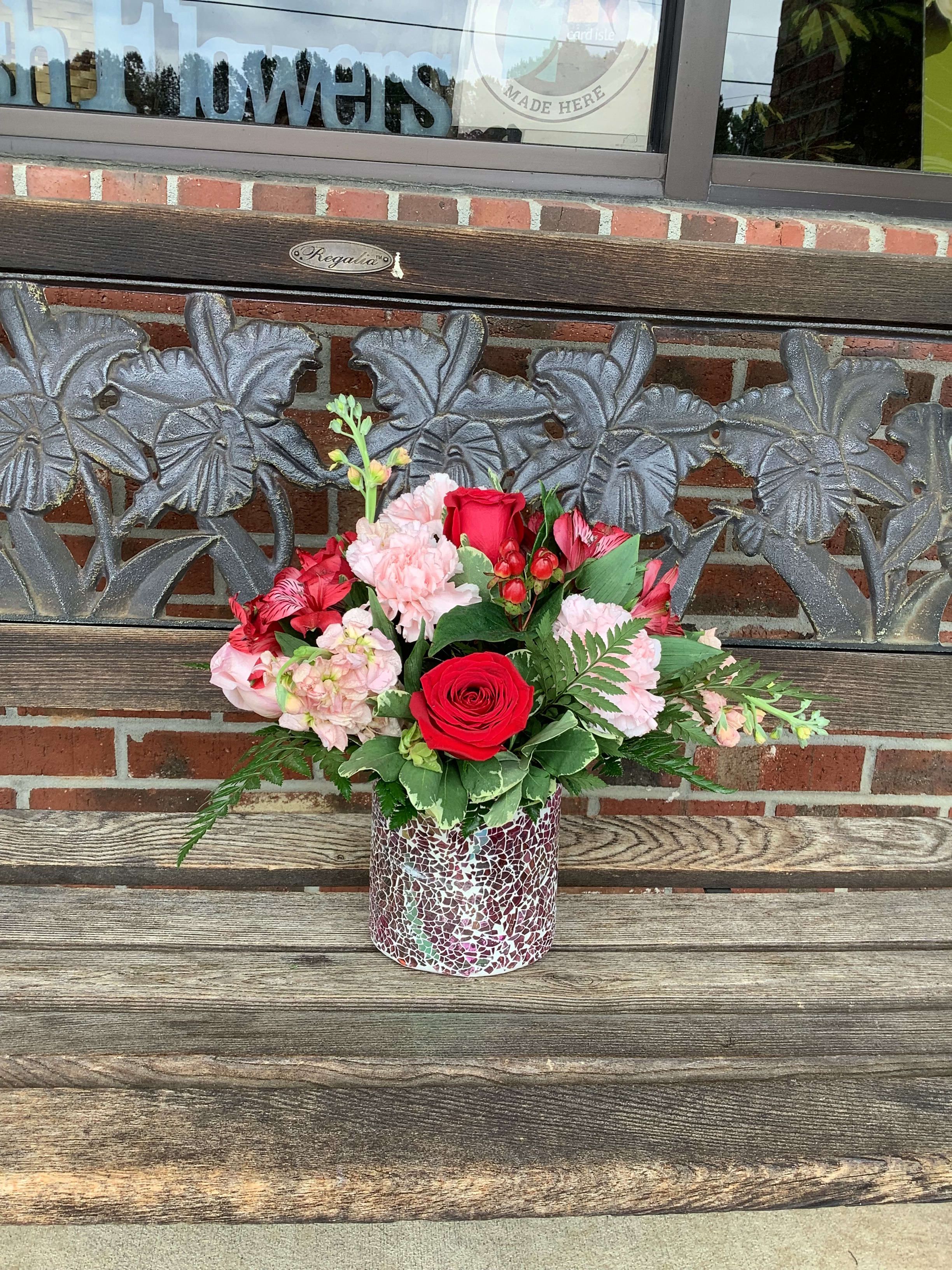 Red and pink flower arrangement in a mosaic vase