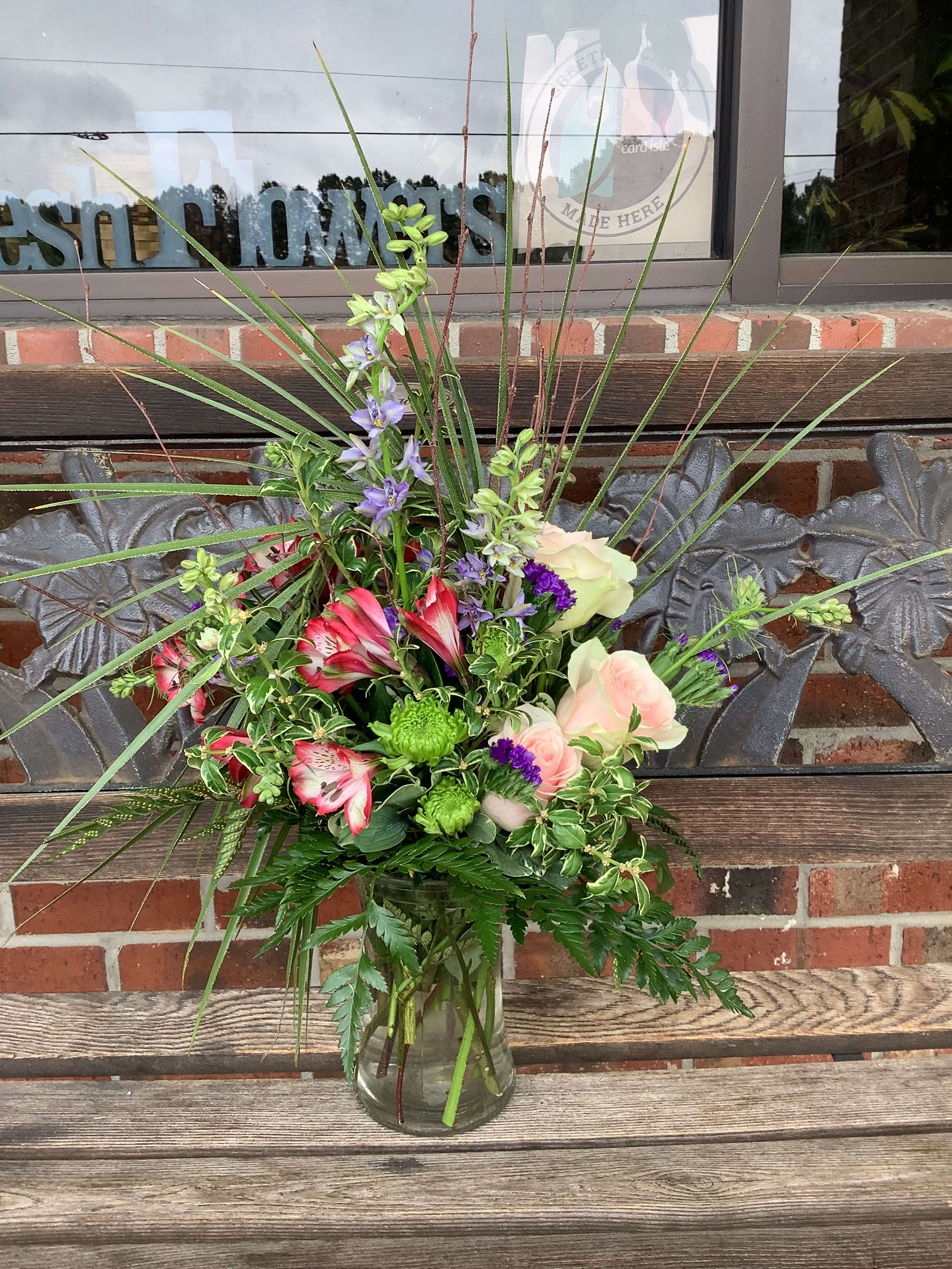 Mixed bouquet in a clear glass vase with pink, purple, and green flowers