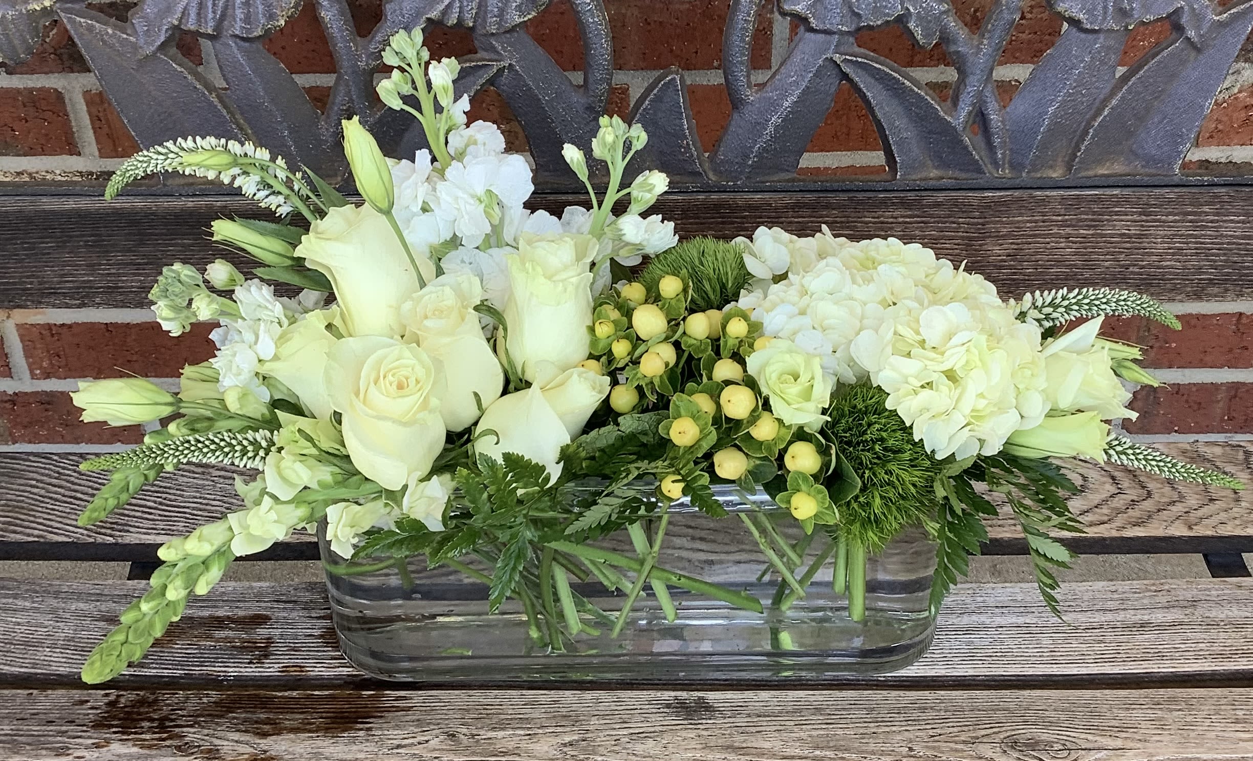 White roses and hydrangeas in a rectangular glass vase