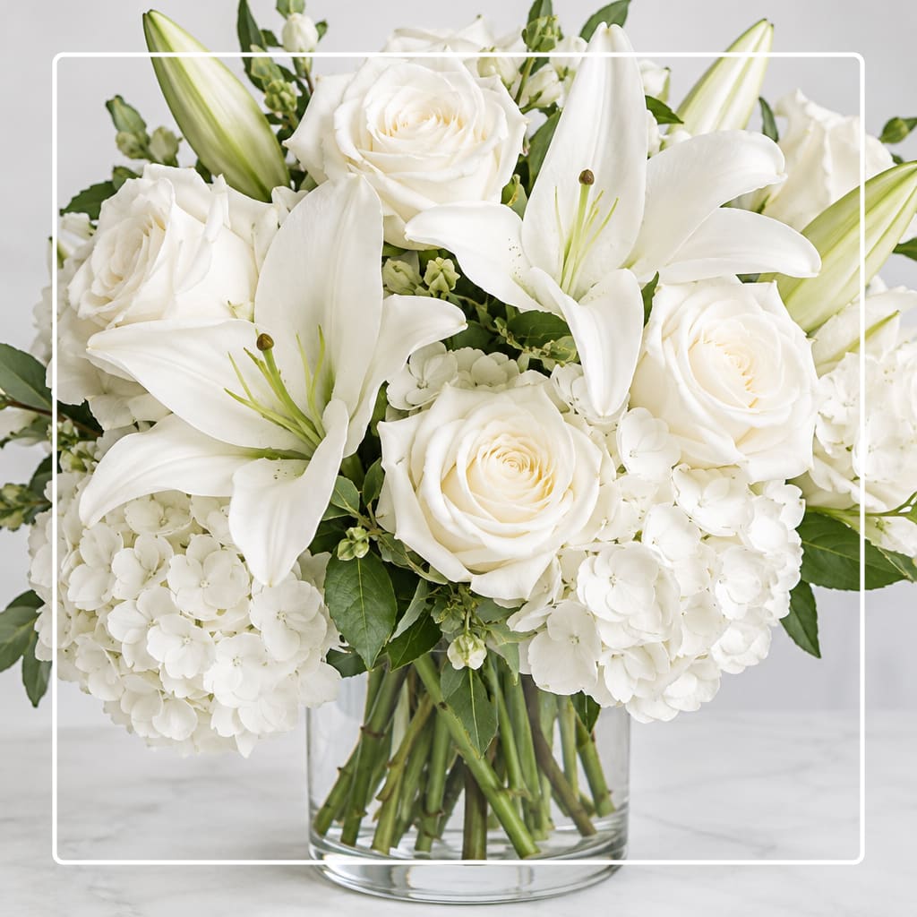 White roses and lilies arranged in a clear glass vase
