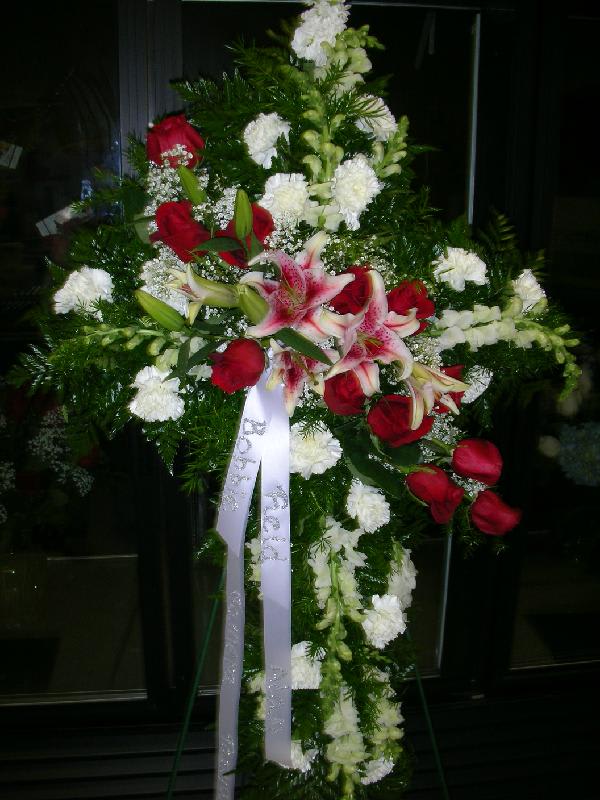 Standing floral spray with red roses, pink lilies, and white blooms