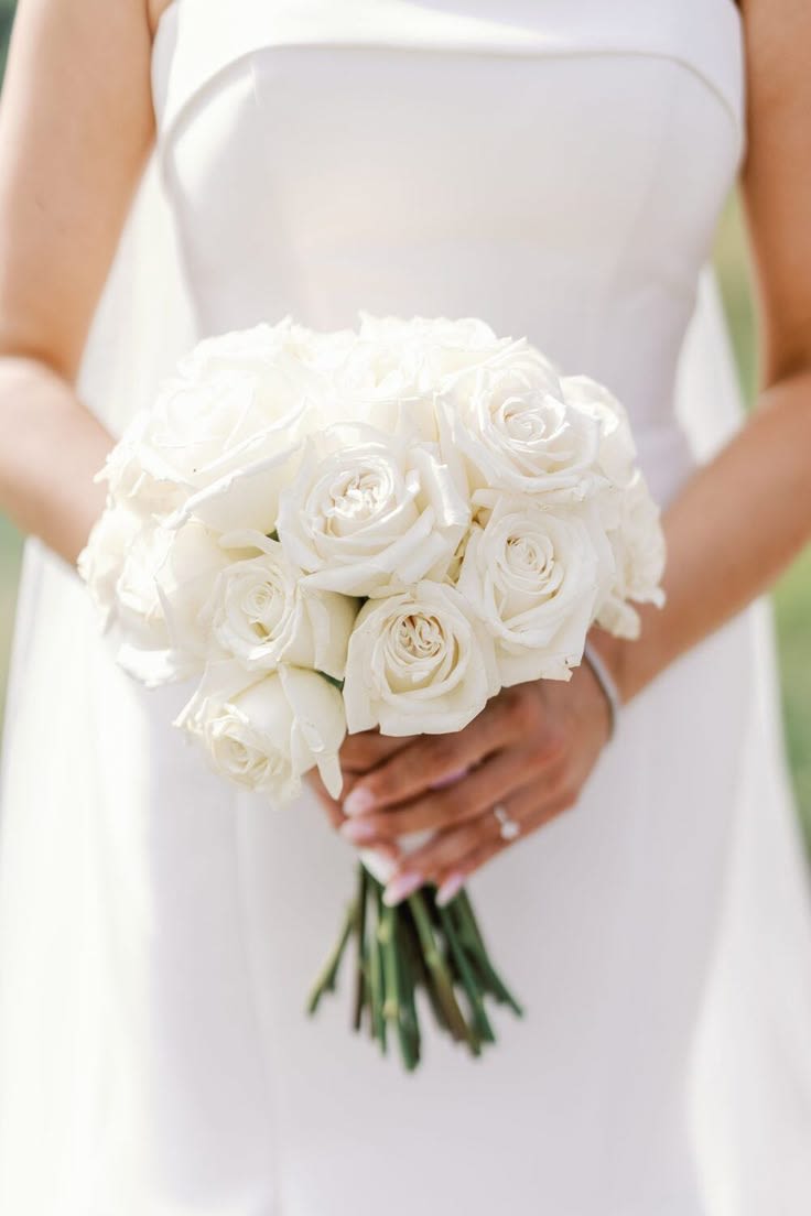 The Simply Forever Bridal Bouquet - Effortless beauty for your most meaningful moment. Our Simply Forever Bridal Bouquet features 18 hand-selected ivory roses, elegantly gathered and finished with a classic ivory satin ribbon wrap.  Designed for the bride who loves timeless simplicity, this no-fuss bouquet offers a soft, romantic look without the stress of customization. It’s graceful, refined, and perfect for celebrating your “I do” moment with ease.  Because sometimes, simple says everything. 
