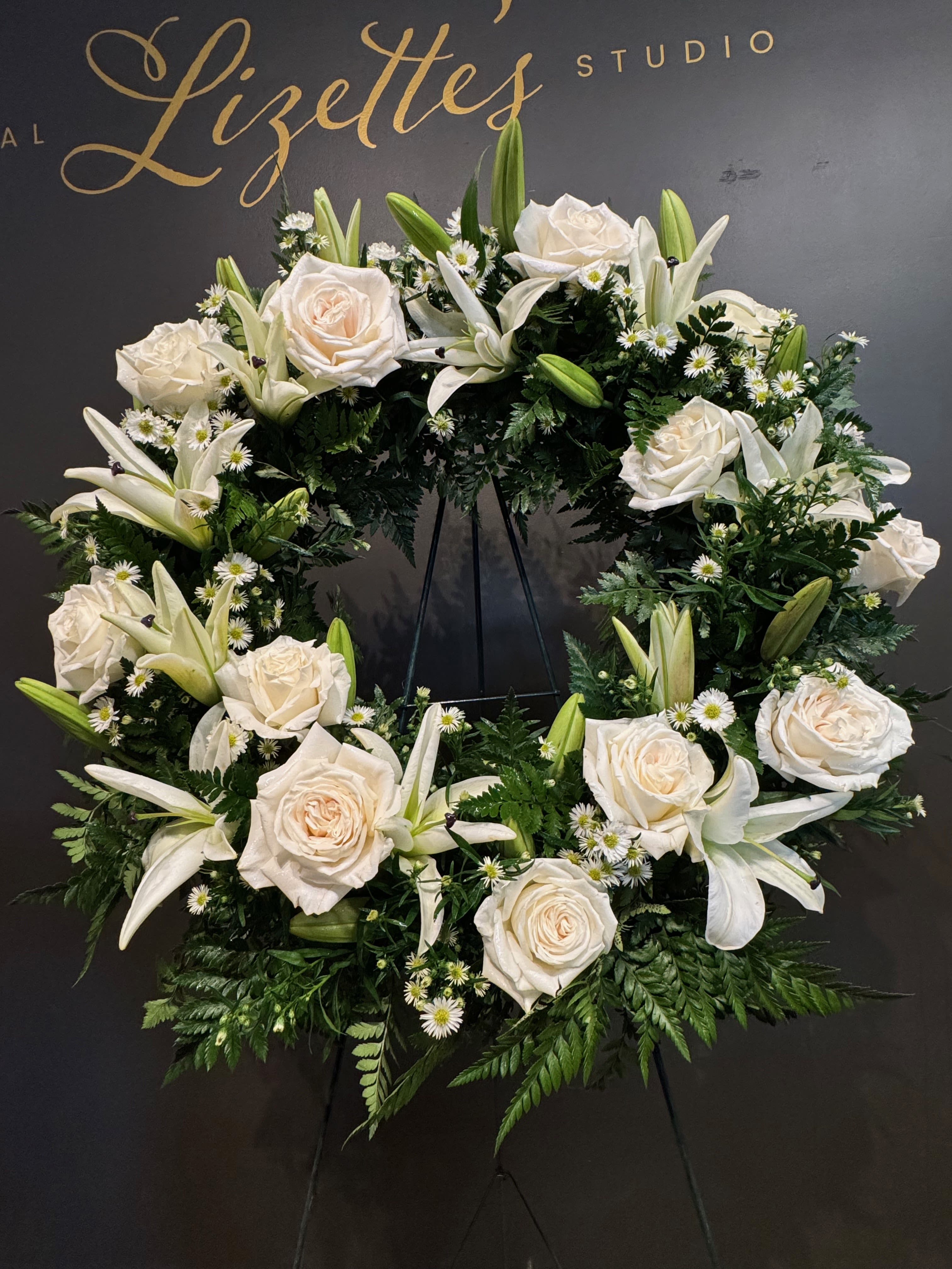Grace Wreath - A simple and elegant sympathy wreath designed with fresh white blooms and lush greenery. Thoughtfully arranged to offer a peaceful expression of love, remembrance, and comfort during times of loss.