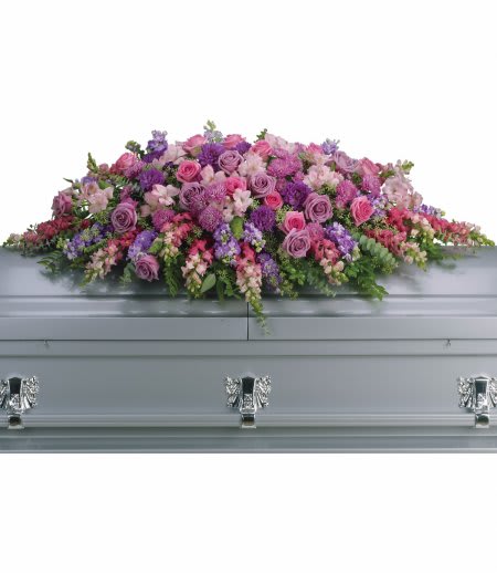 Large pink and purple casket spray of roses and mixed flowers on a silver casket
