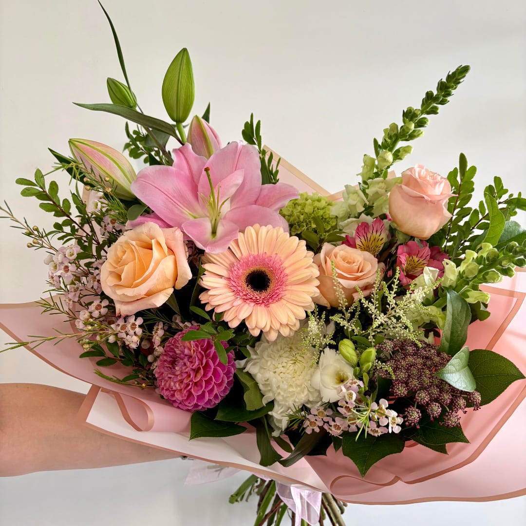 Handheld bouquet with pink lilies, peach roses, and a pink gerbera daisy