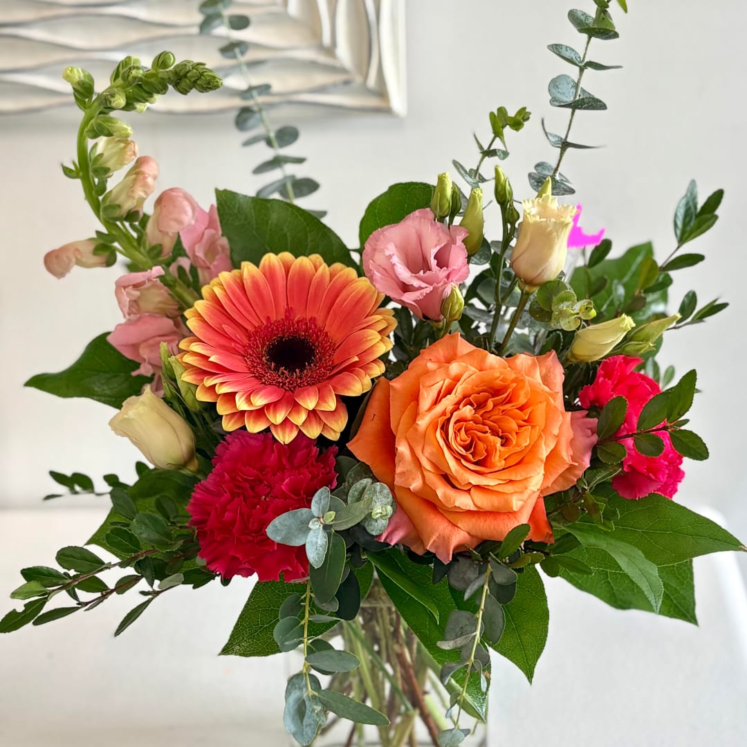 Mixed bouquet with orange gerbera, orange rose, pink lisianthus, and carnations in a vase