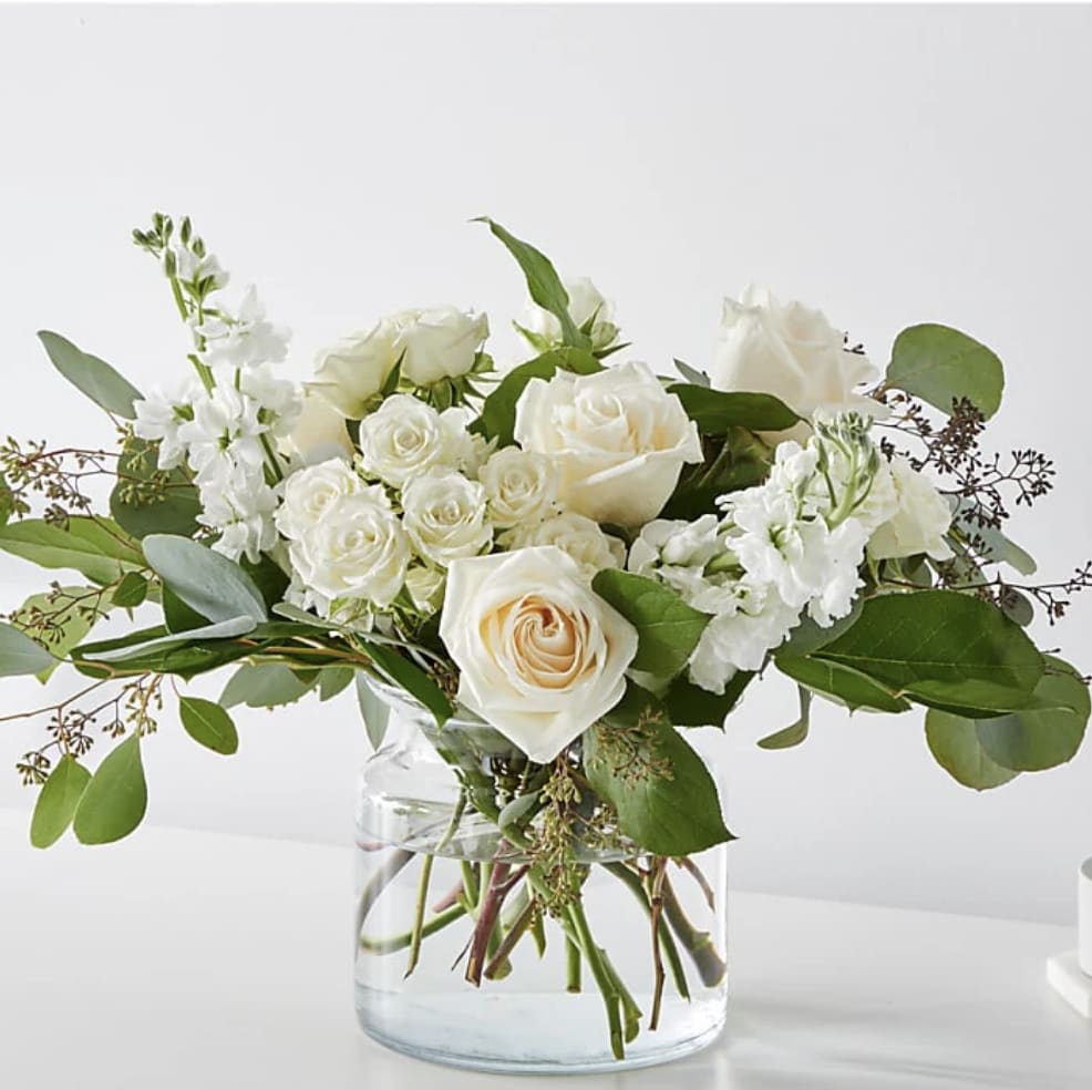 White roses and white blooms in a clear glass vase