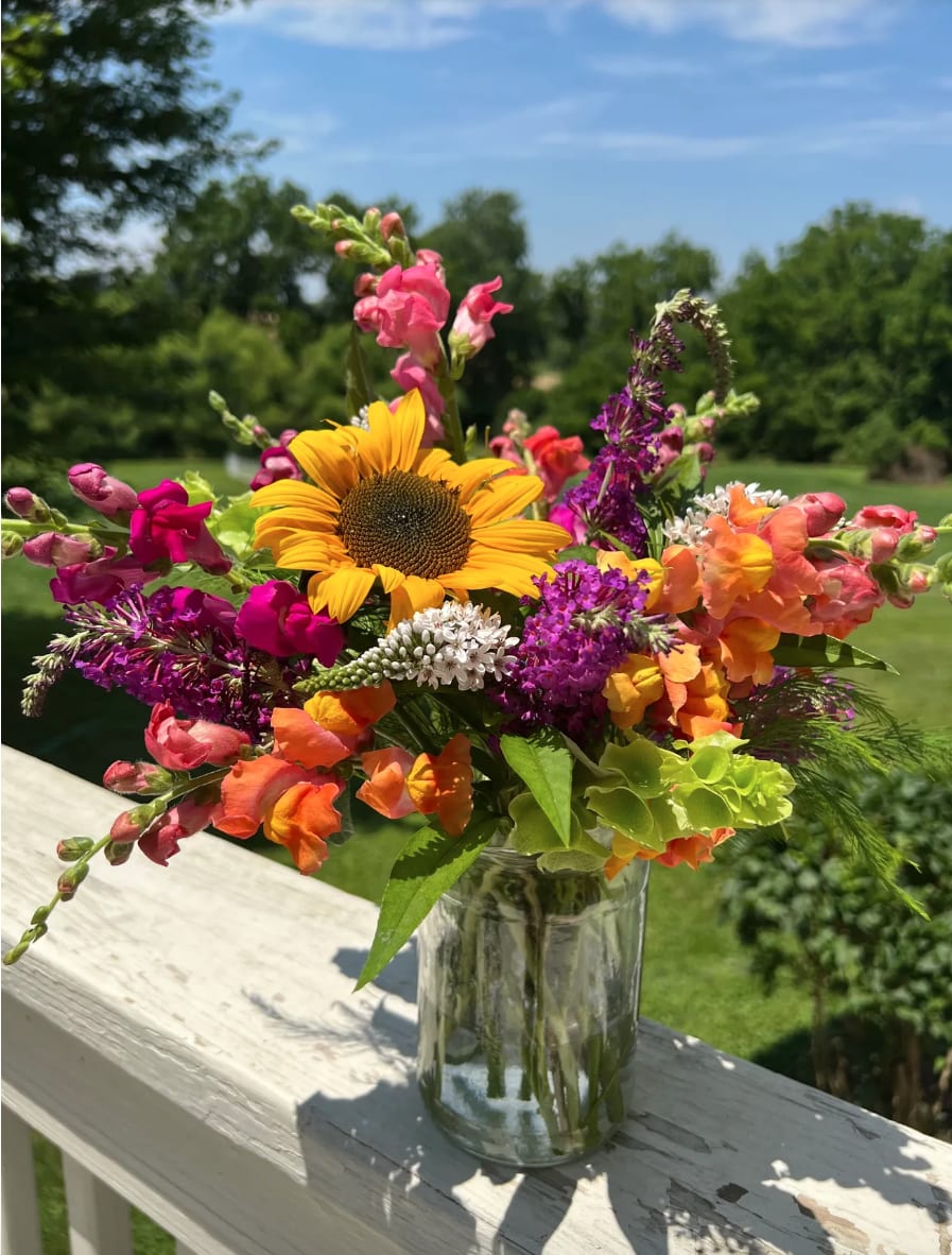 Colorful bouquet with a sunflower and snapdragons in a glass vase