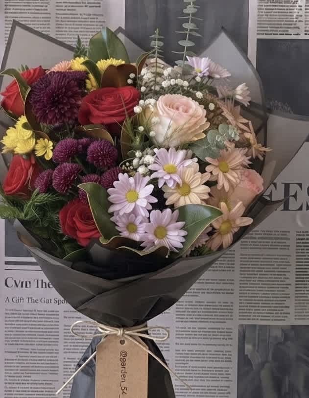 Mixed bouquet of roses and daisy-like flowers wrapped in black paper