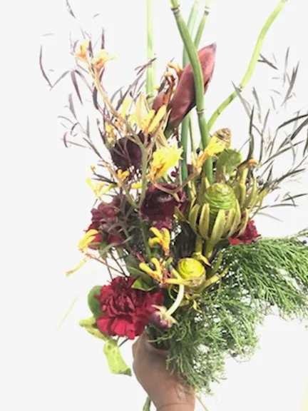 Tall tropical bouquet with red and yellow flowers in a hand