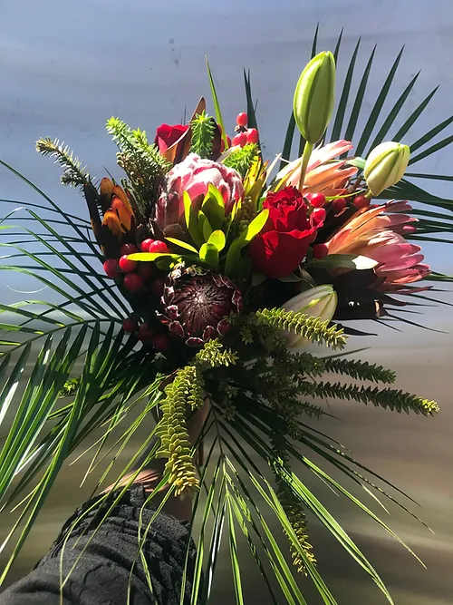 Tropical bouquet with protea, lilies, and red roses