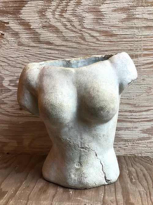 Torso-shaped ceramic planter on a wooden surface