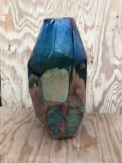 Blue iridescent geometric glass vase on a wooden surface