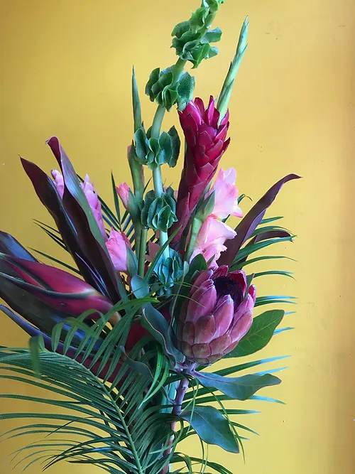 Tropical floral arrangement with pink protea and tall green spikes