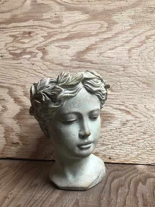 Stone-colored decorative bust of a woman with closed eyes