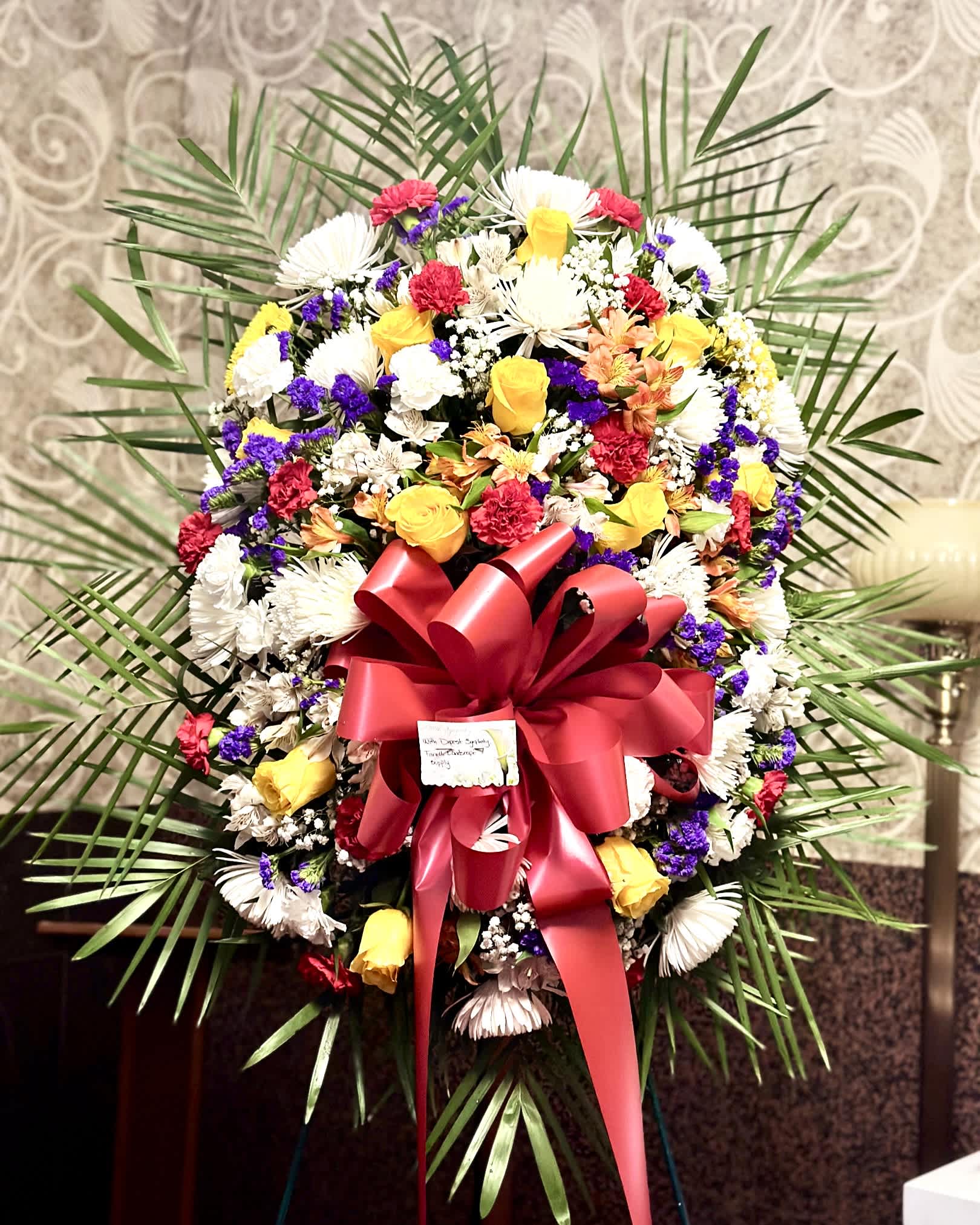 Mix of flowers standing spray.  - With sympathy of a special person lost, this standing spray is fill with red carnation, yellow roses, white spiders, purple stocks, and  more.