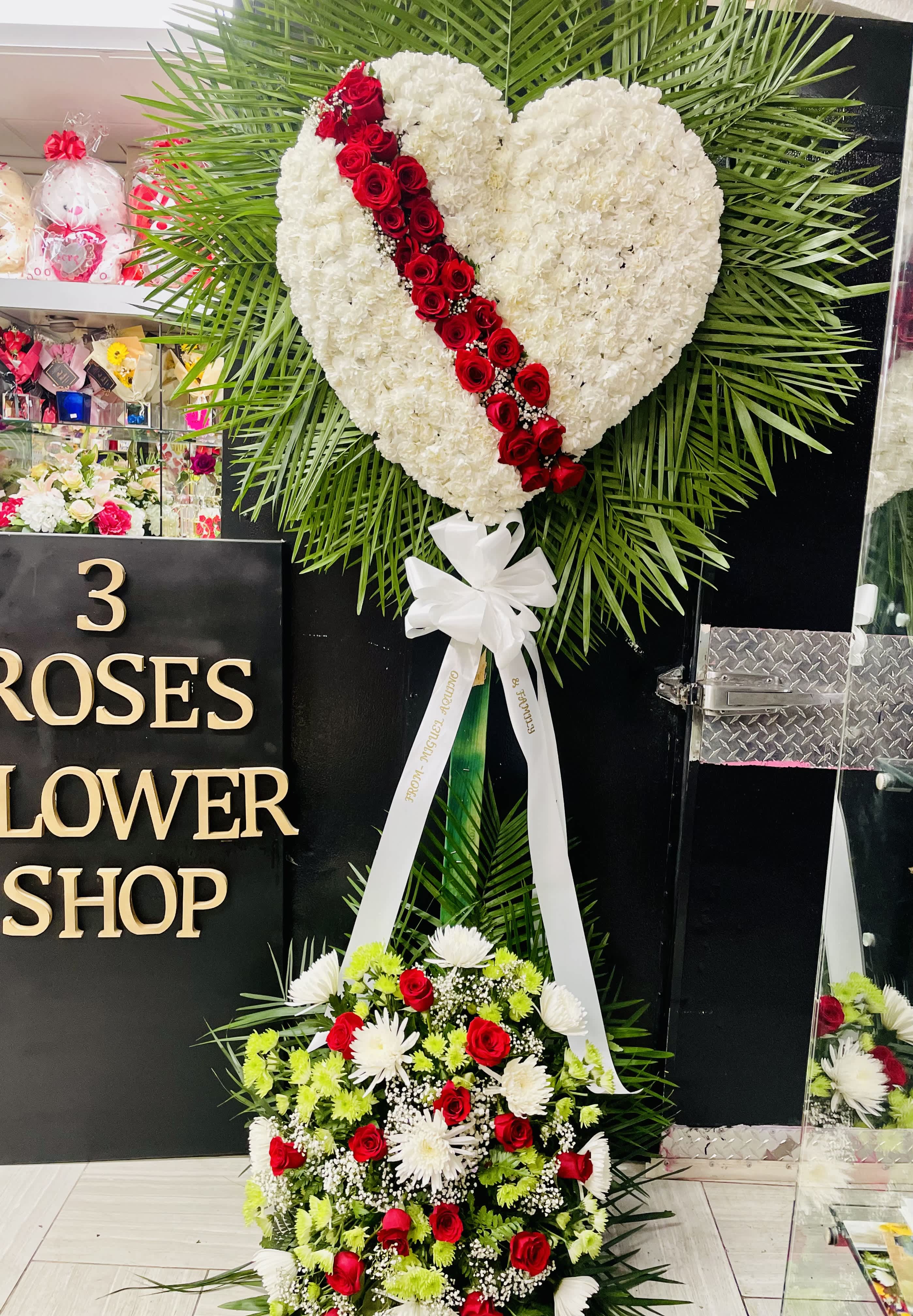 In memory of your loss. By 3 Roses Flower Shop - Close heart spray with sympathy of a lost family. This heart spray is fill with White Carnations, Red Roses across the heart it is about 6ft tall with basket in the bottom to fill in.  