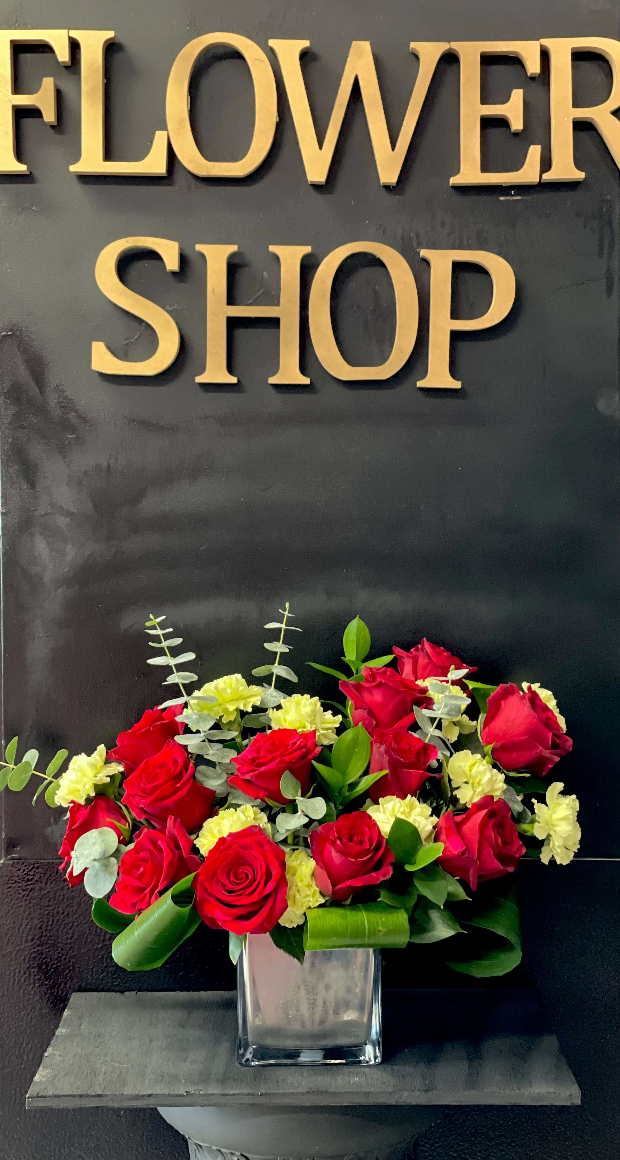 12 roses -by 3 Roses Flower Shop. - 12 Red Roses in a vas with green carnations and eucalyptus.  