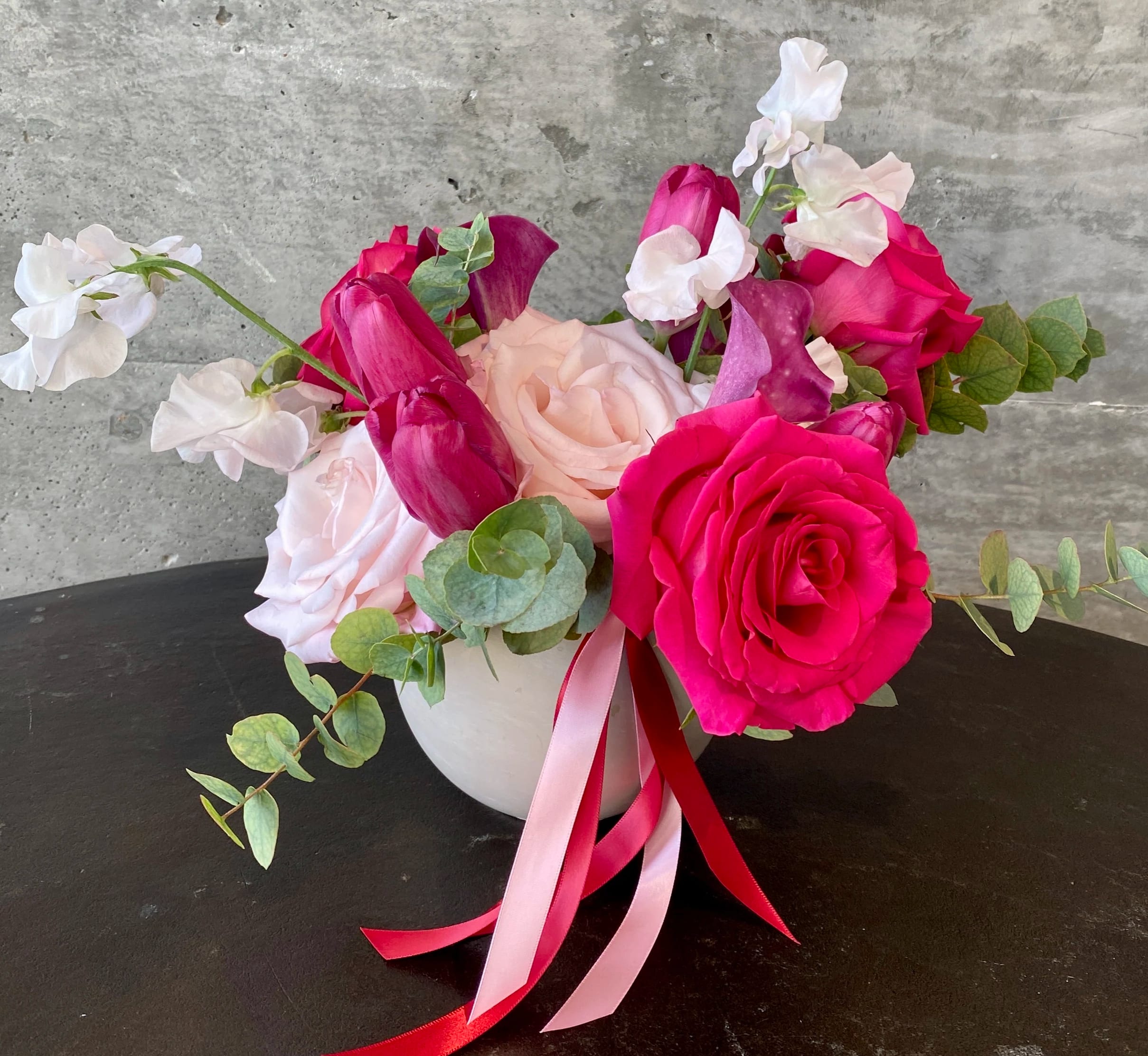 Pink and white rose bouquet in a white vase with ribbon