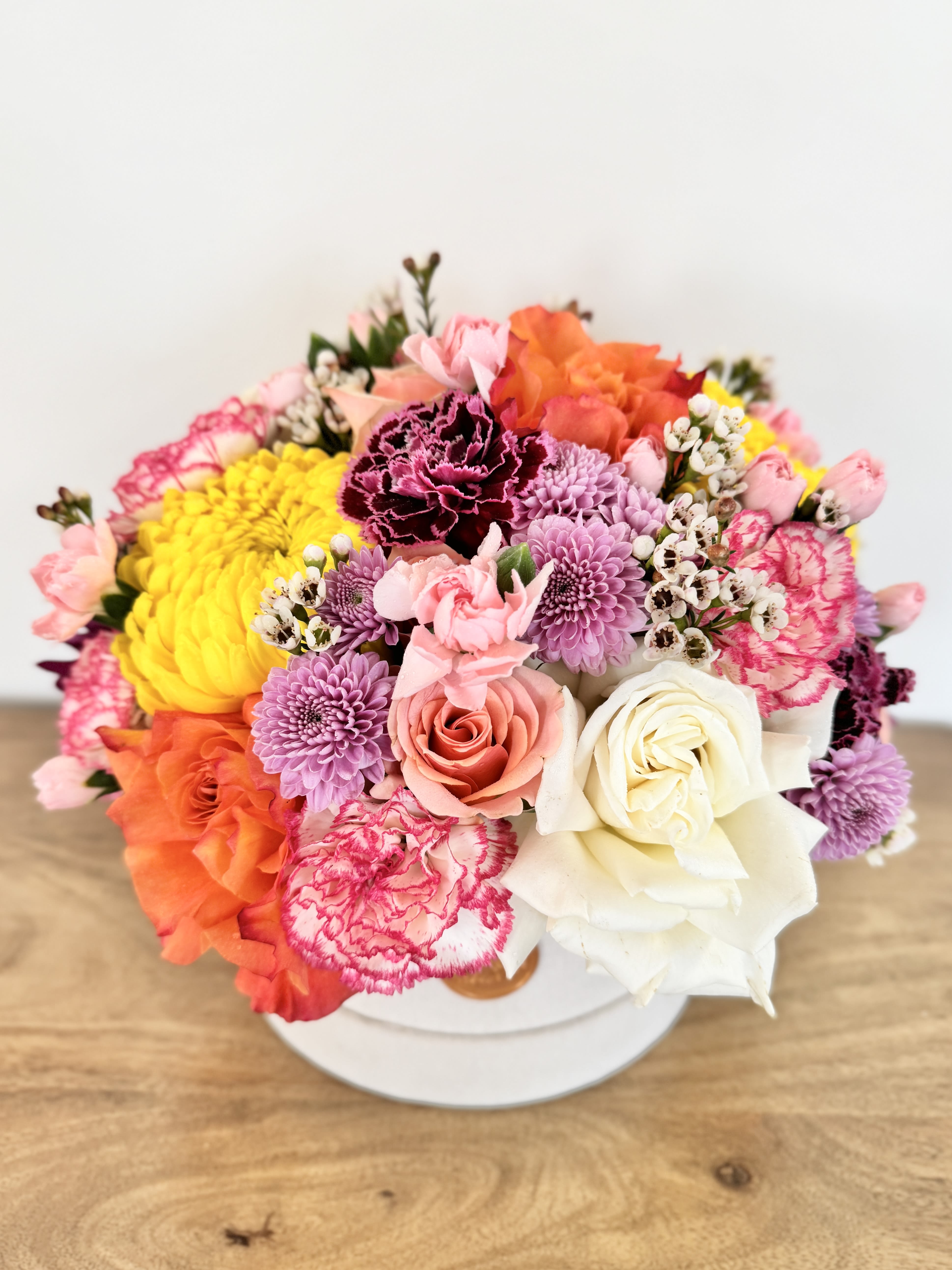 Colorful bouquet of roses, carnations, and chrysanthemums in a white box