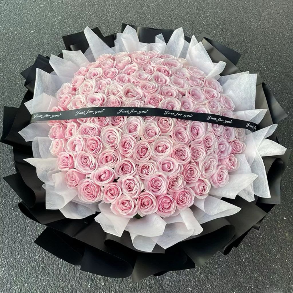 Large bouquet of pale pink roses wrapped in black and white paper