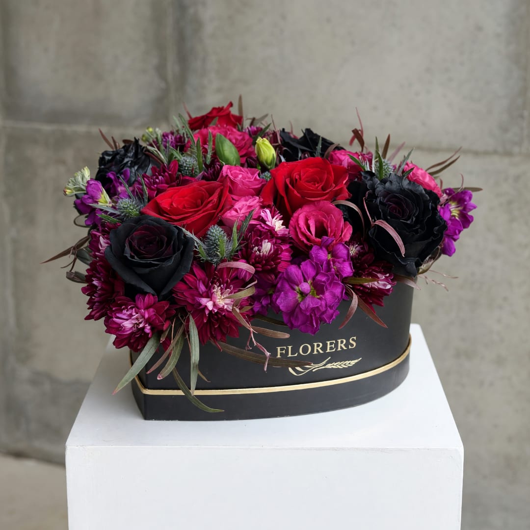 Red, pink, and black roses in a black hat box