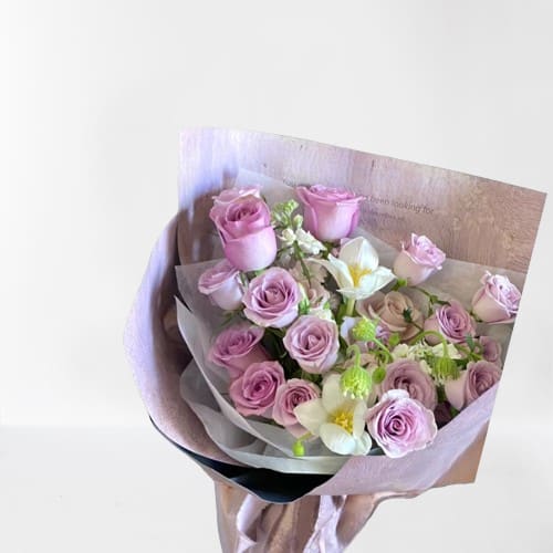 Bouquet of pink roses and white flowers wrapped in pale paper