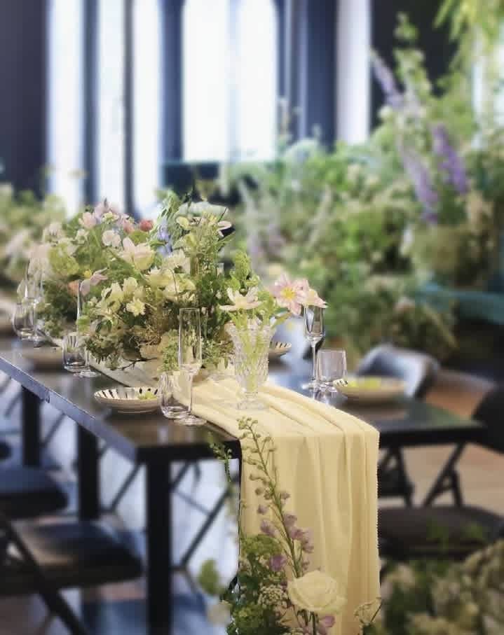 Pastel floral centerpiece on a table with a pale draped runner