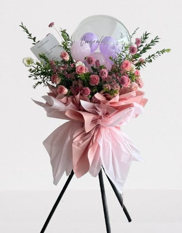 Pink rose bouquet with balloons and a card on a stand
