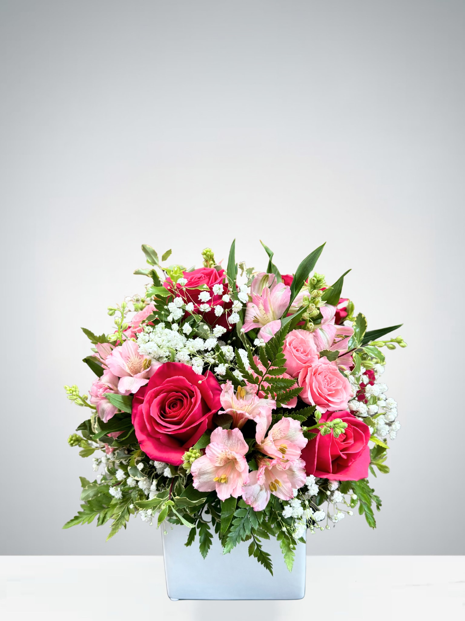 Pink roses and alstroemeria in a square glass vase