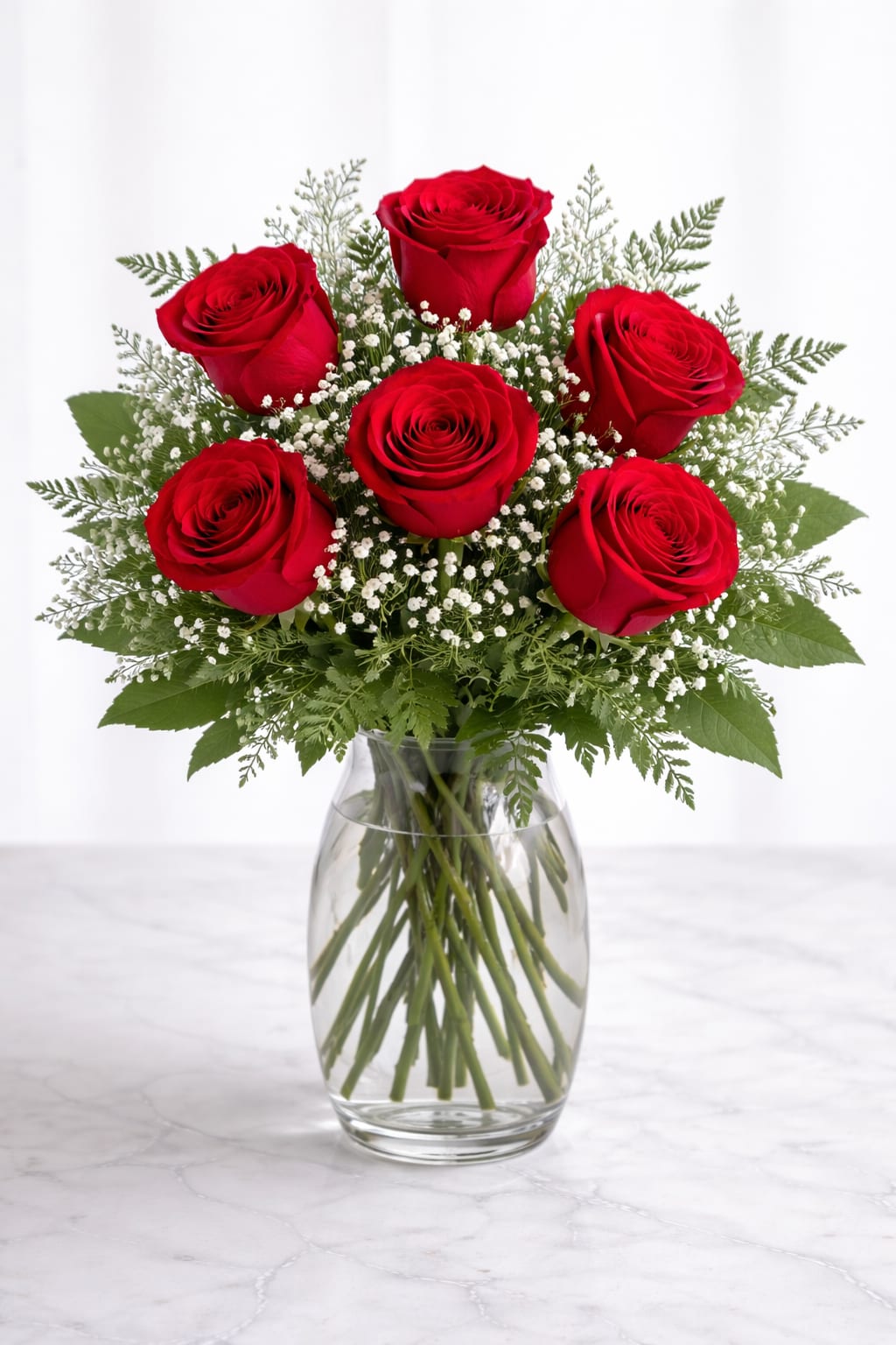 Six red roses in a clear glass vase with baby's breath