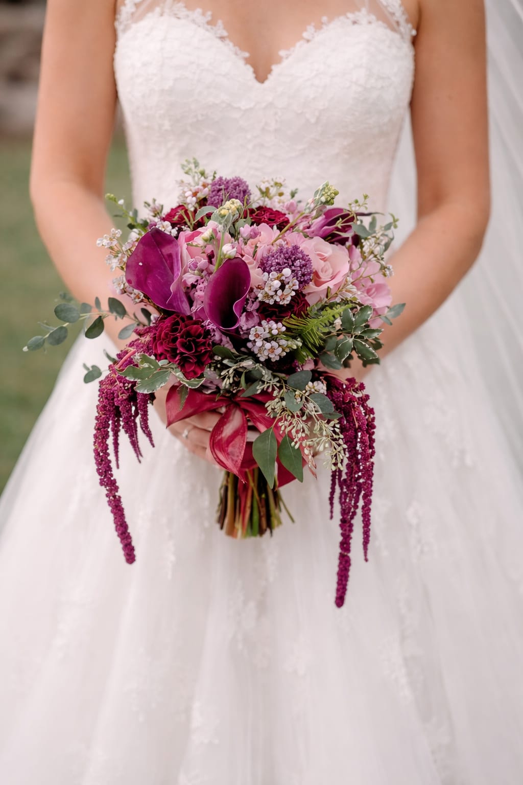 Bride holding a cascading bouquet of pink and burgundy flowers