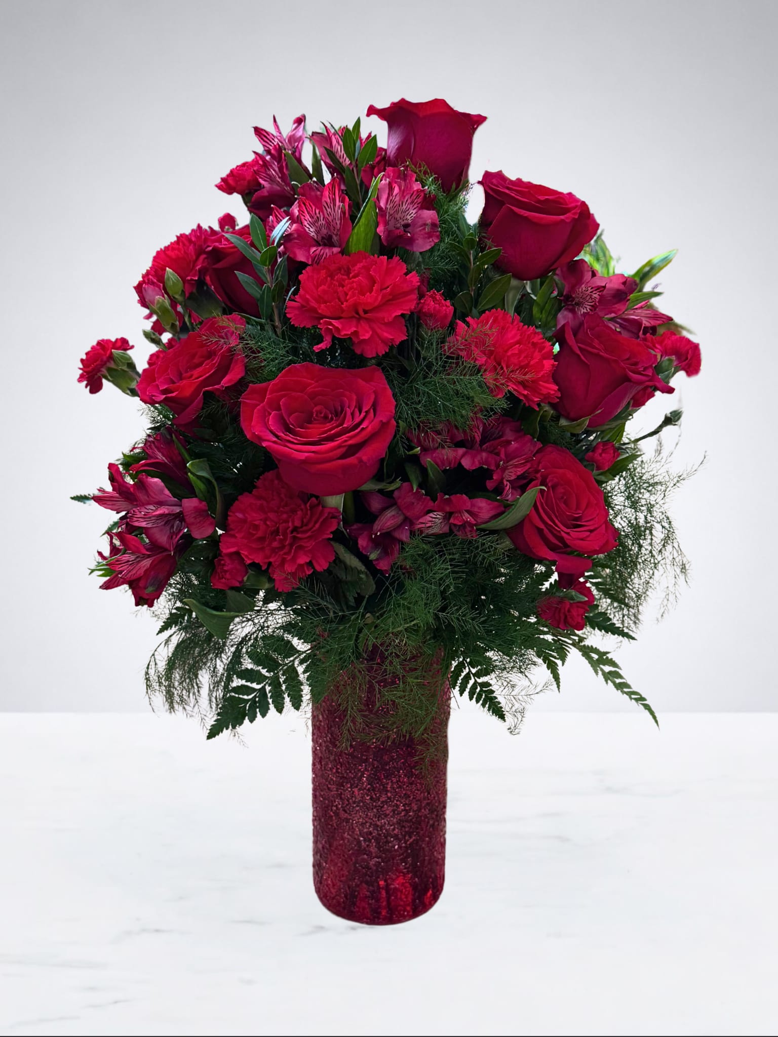 Red roses and carnations arranged in a glittery vase