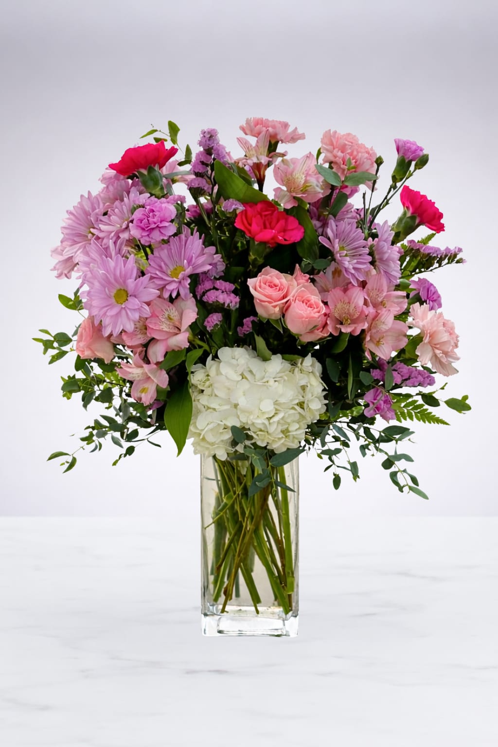 Mixed pink and white flowers arranged in a clear glass vase