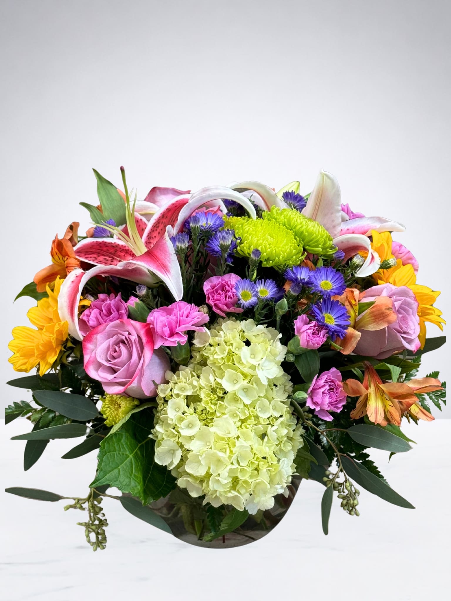 Mixed bouquet with pink lilies, roses, and hydrangea in a glass vase