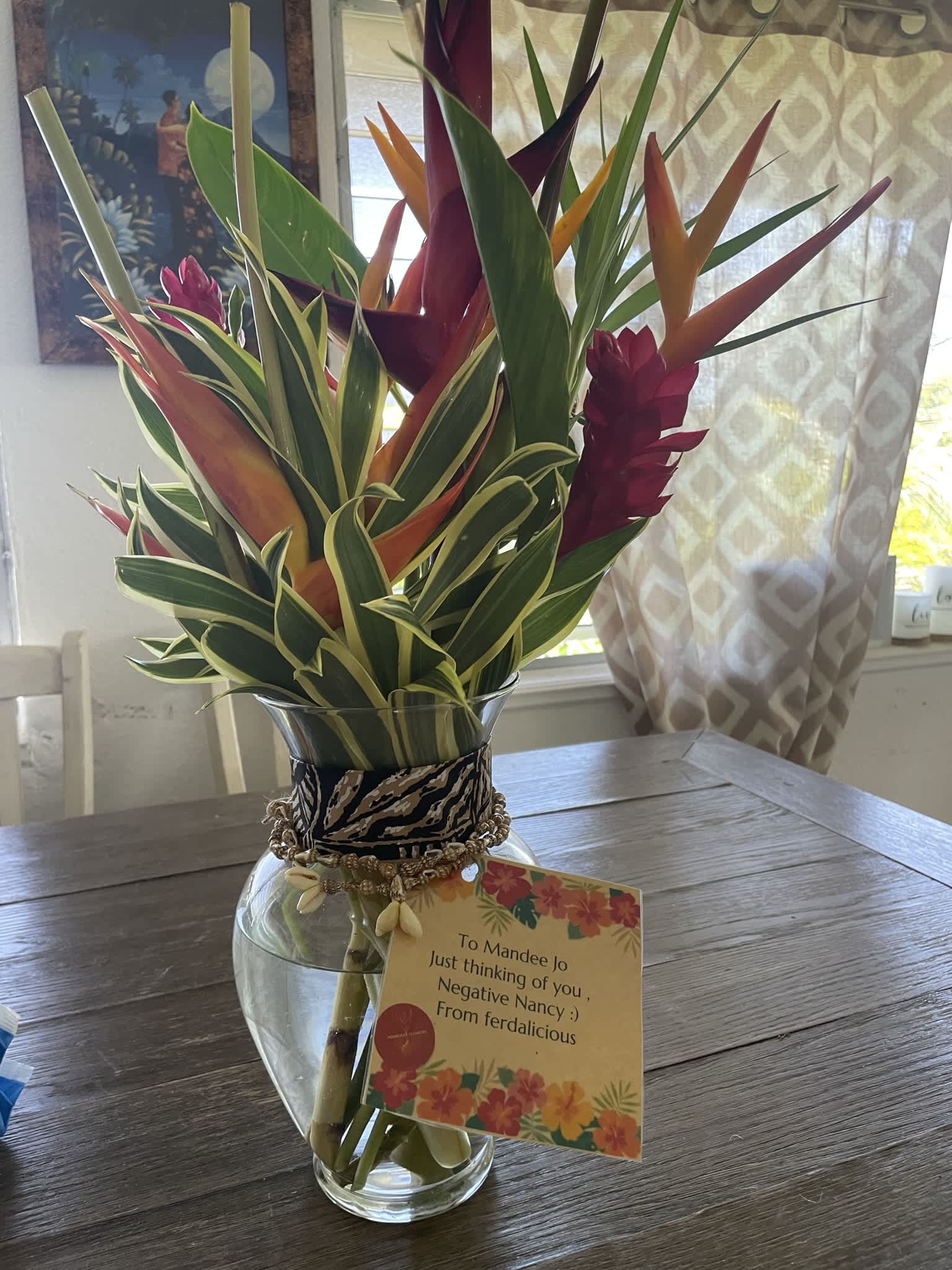 Tropical bouquet in a glass vase with a gift tag