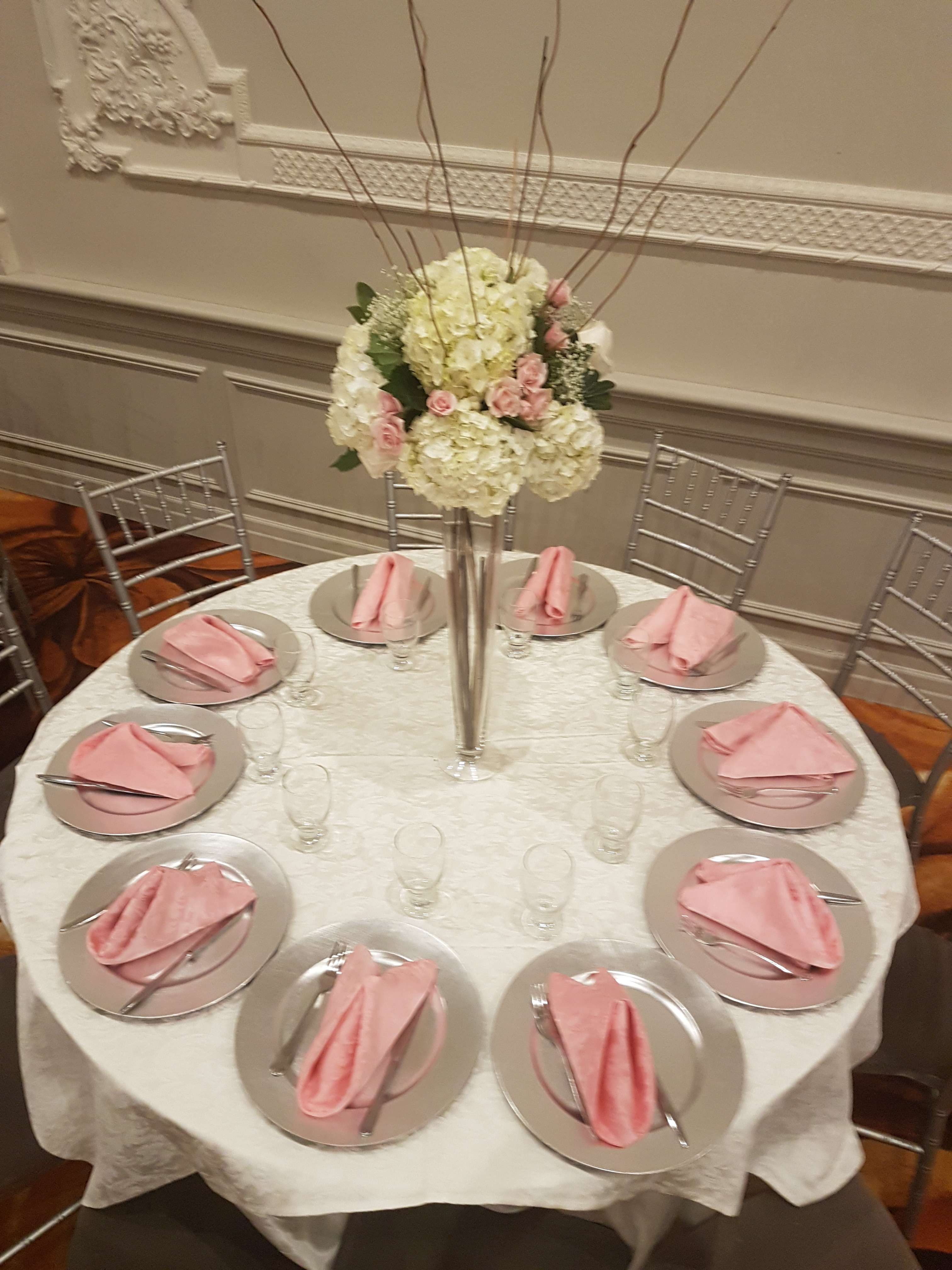 Tall floral centerpiece with white and pink blooms on a banquet table