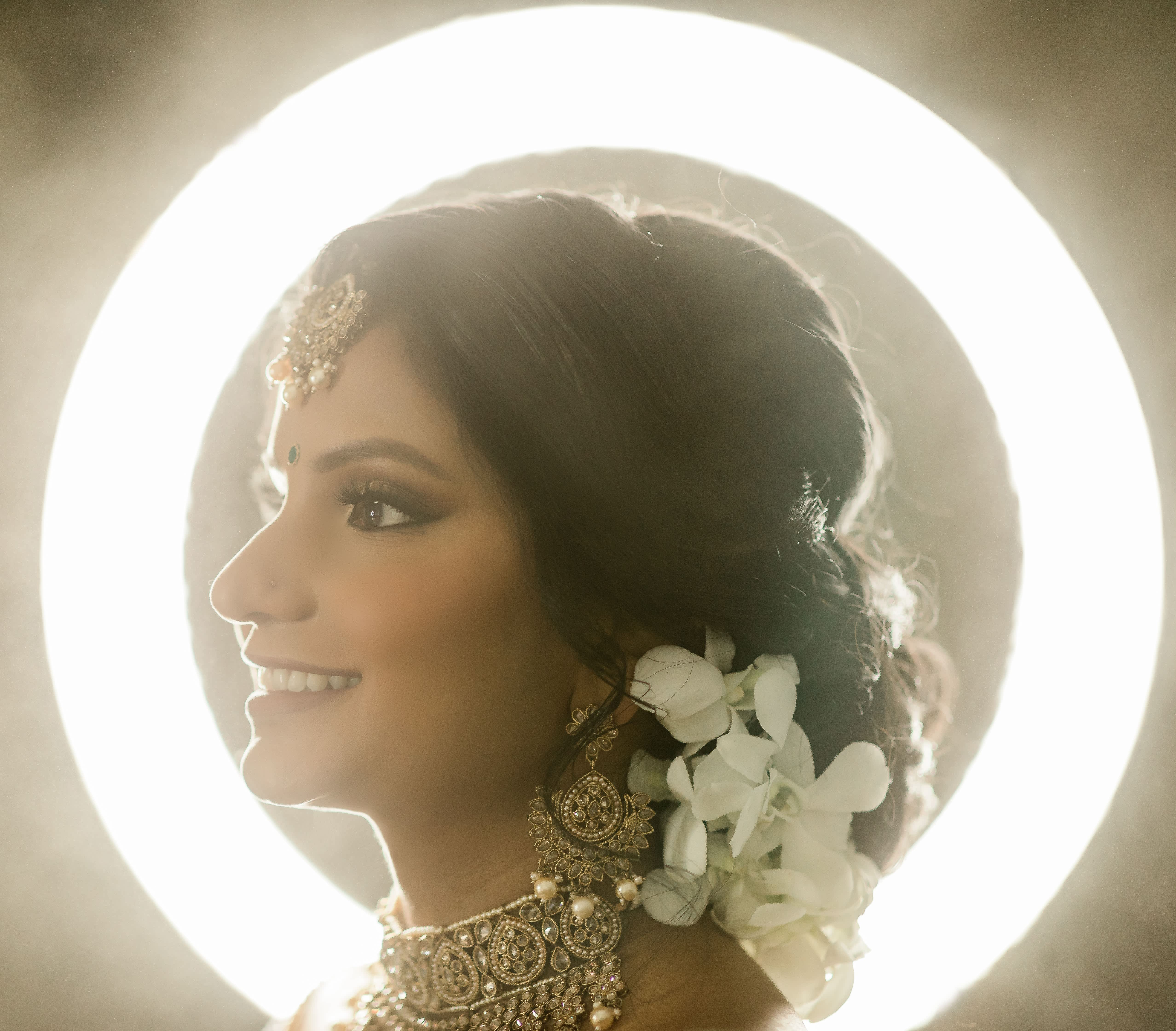 Bride in profile with white flowers in her hair and ornate jewelry