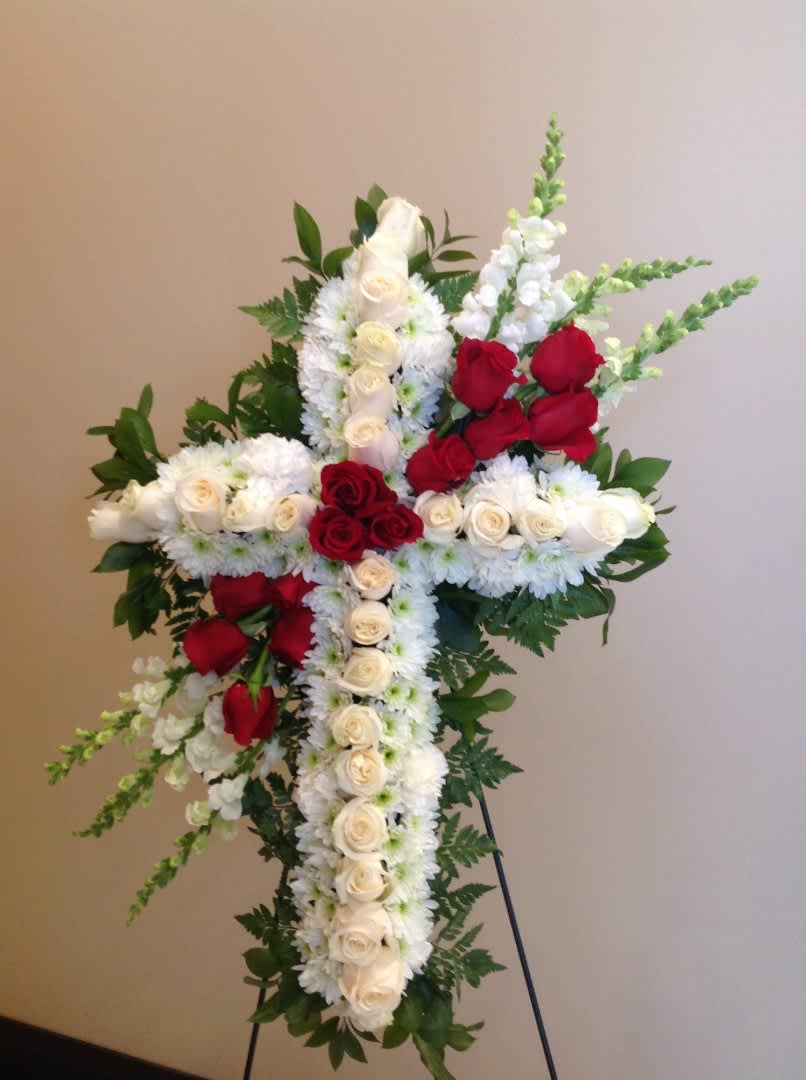 Cross-shaped floral arrangement with red and white roses on a stand