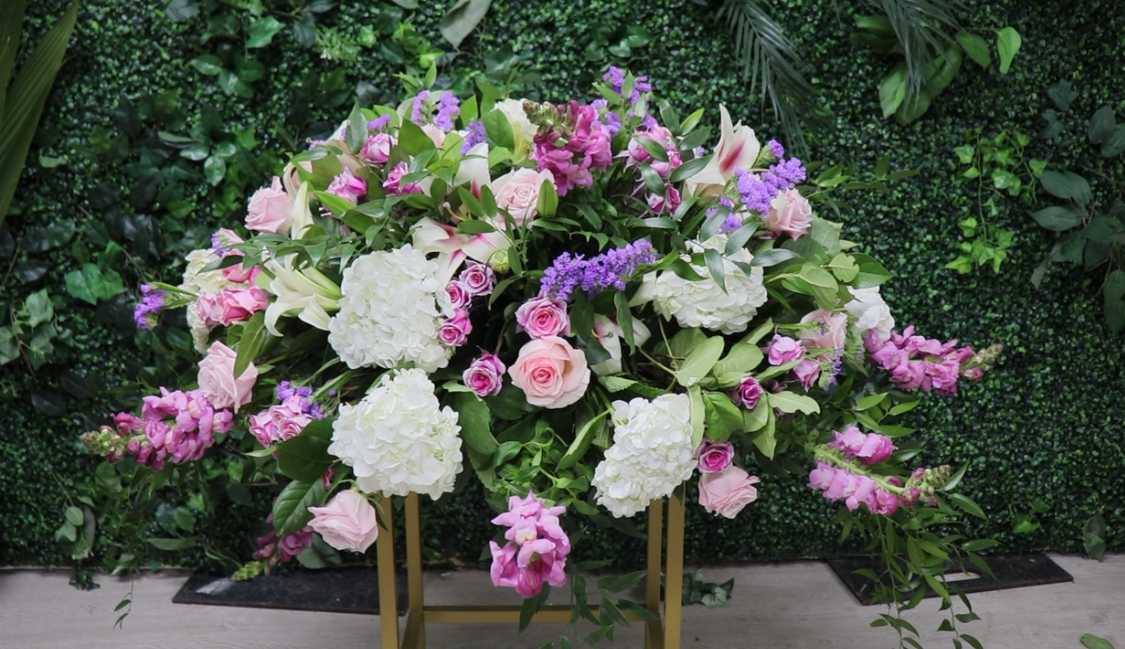 Large pink, white, and purple floral arrangement on a gold stand