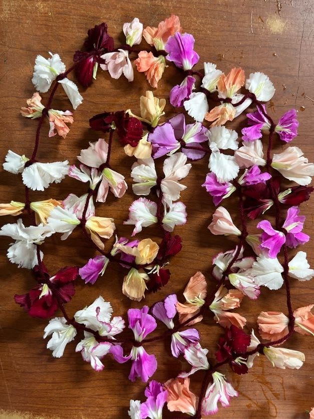 Scattered small blossoms in pink, white, peach, and burgundy on a wooden surface