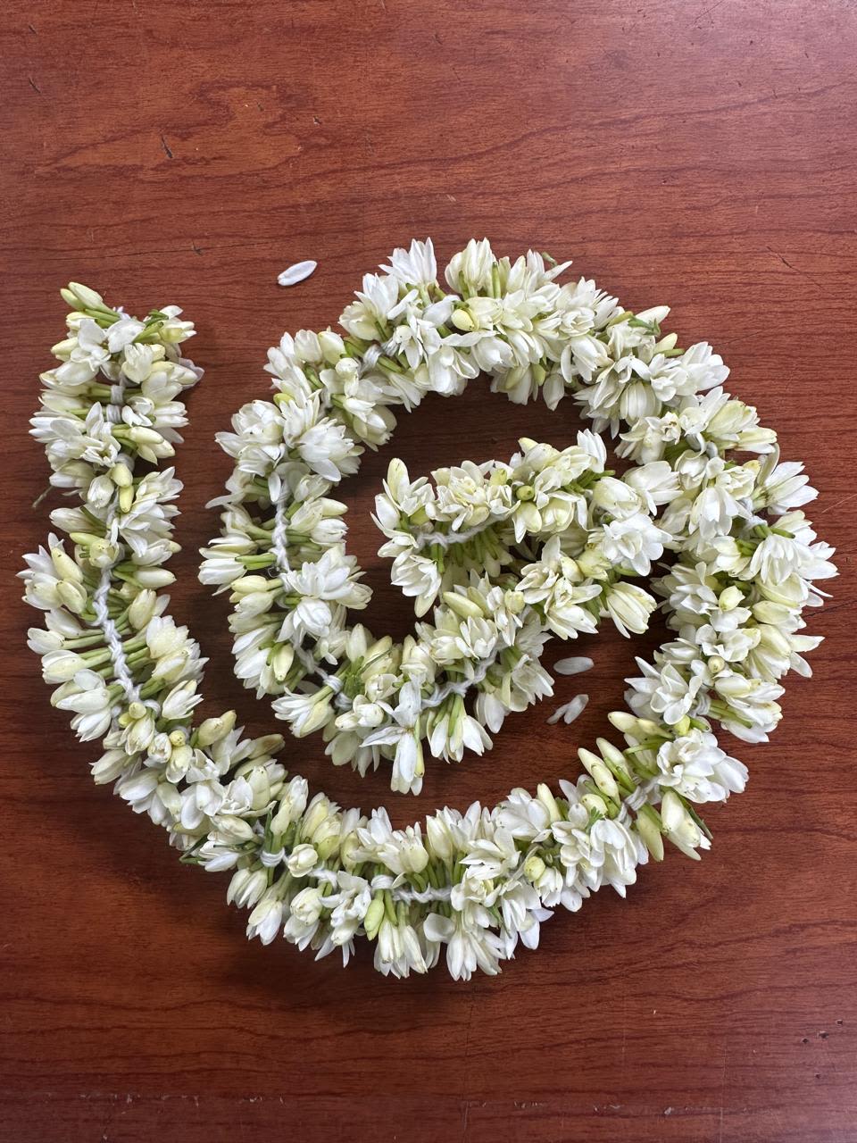 White flower garlands arranged in loops on a wooden surface