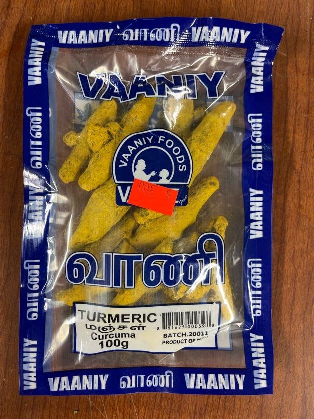 A plastic bag of turmeric roots on a wooden surface.