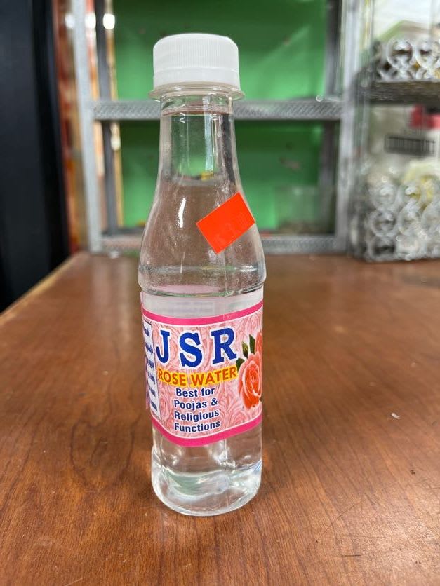 Bottle of rose water with a pink label on a wooden table