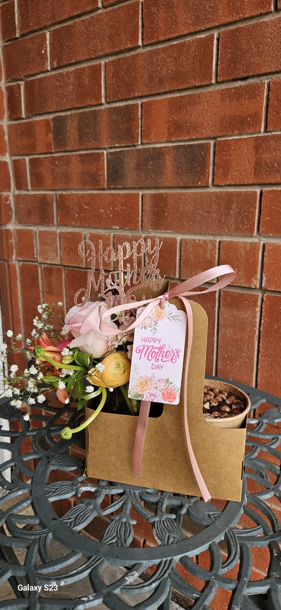 Pink and yellow flower arrangement in a kraft gift bag with a Mother's Day tag