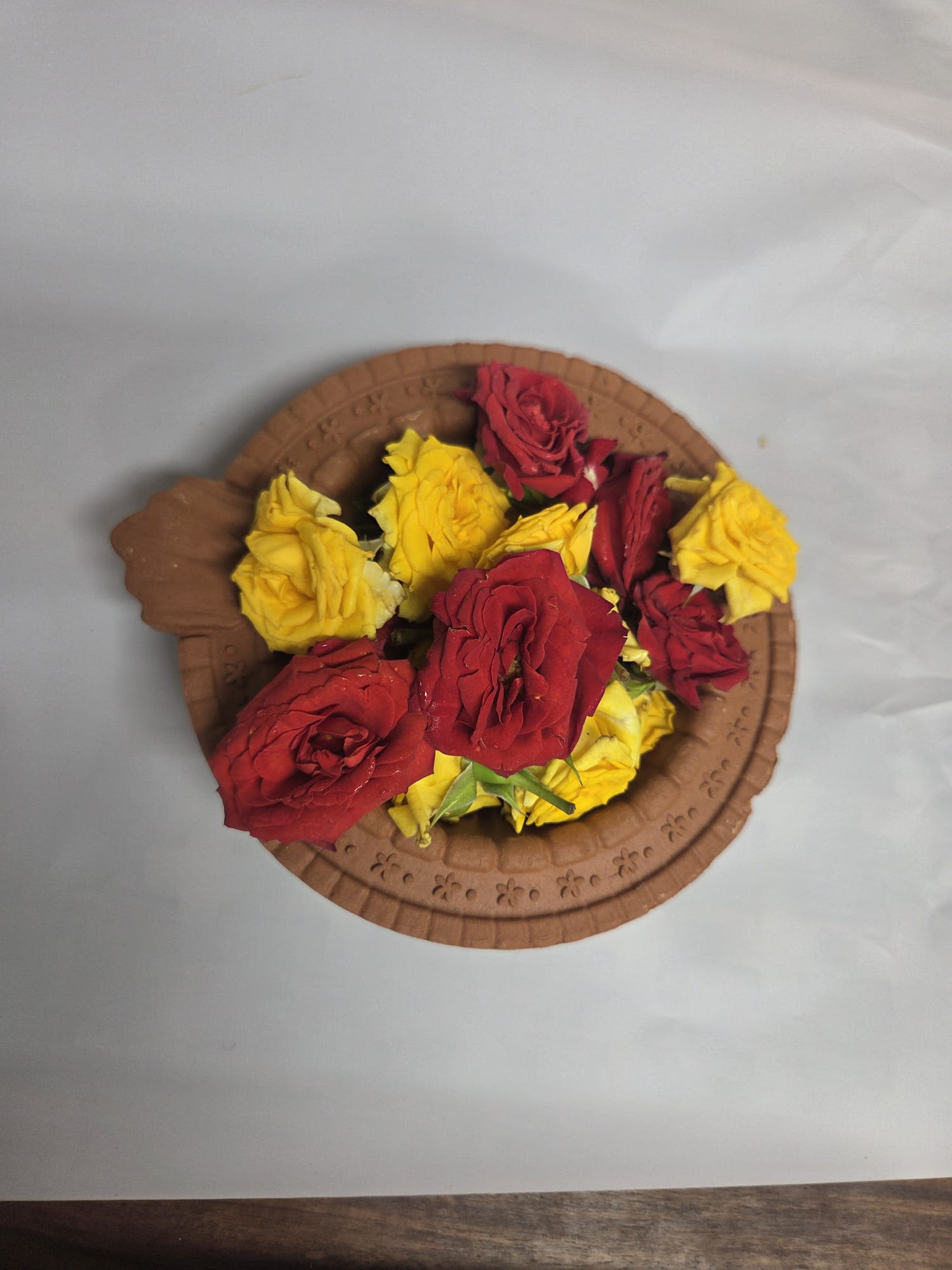 Red and yellow roses arranged on a round brown tray
