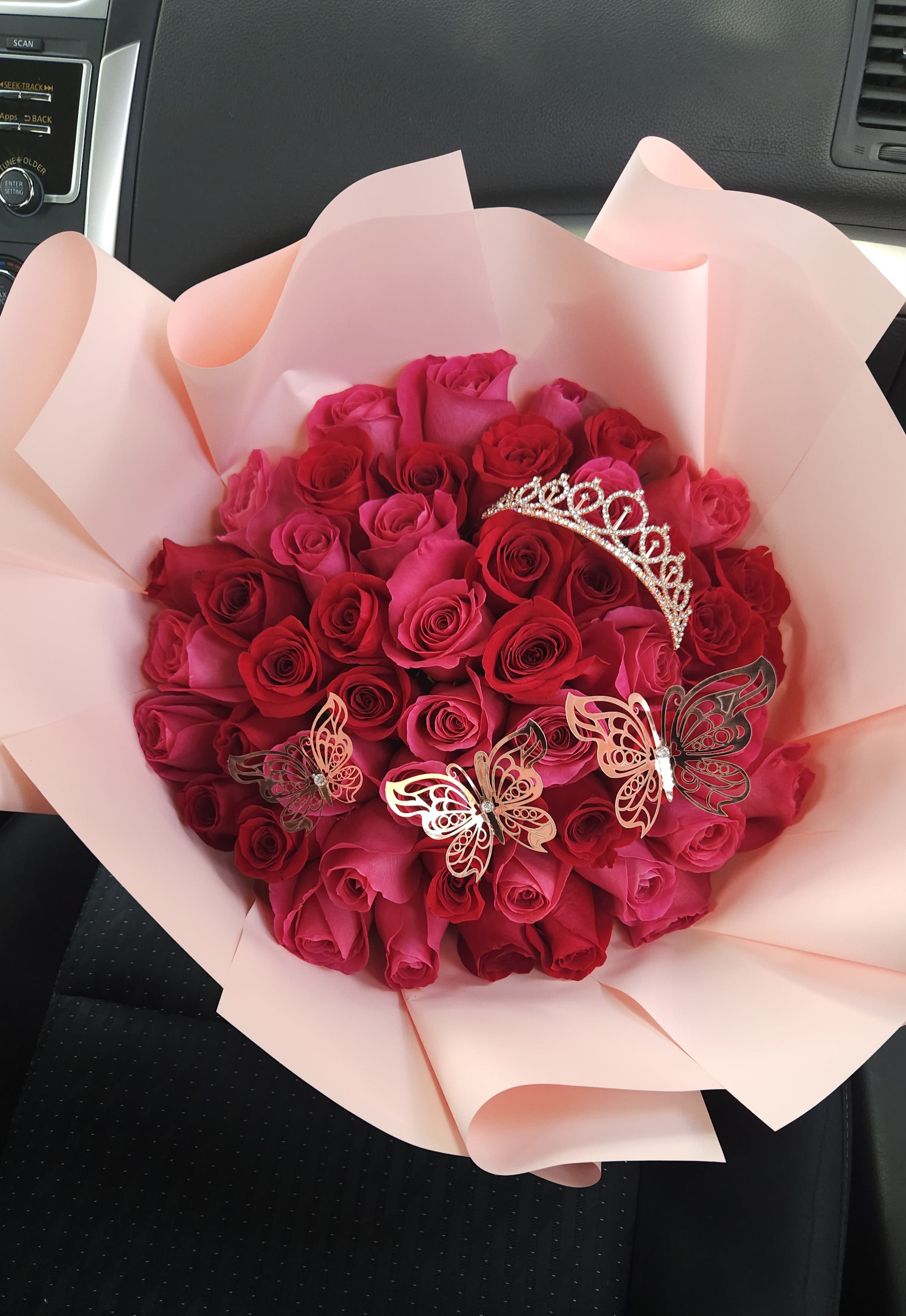 Bouquet of pink and red roses with butterfly decorations and a tiara