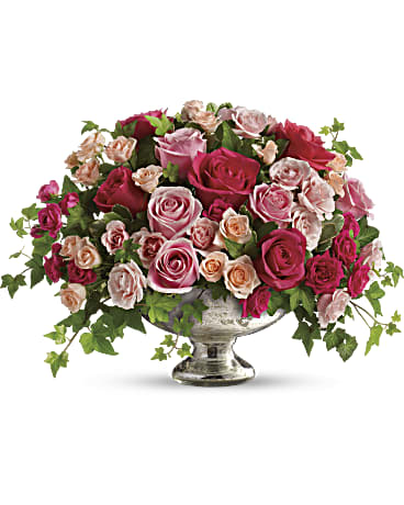 Pink and peach roses arranged in a silver pedestal vase