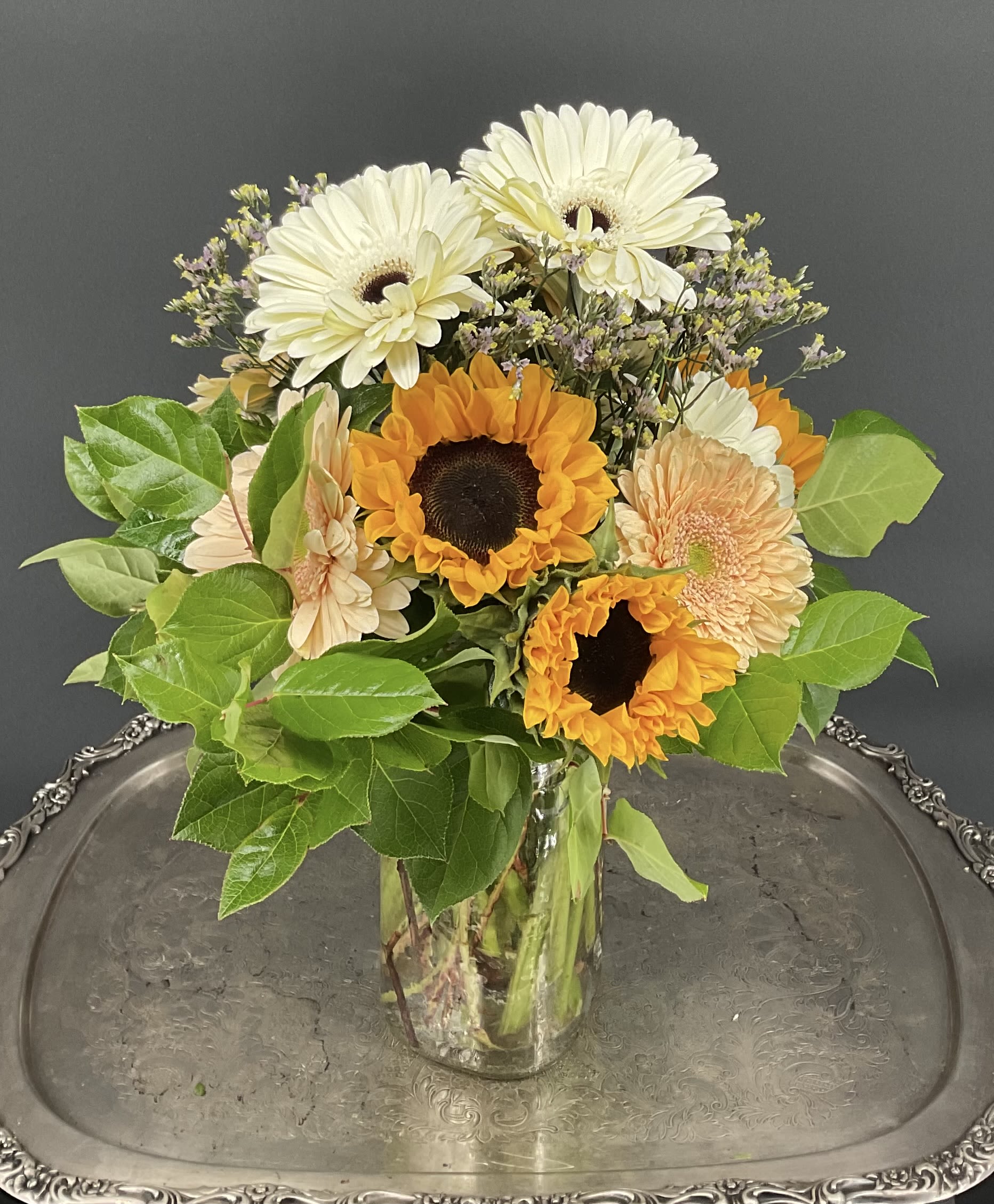 Sunflowers and pale gerbera daisies in a clear glass vase